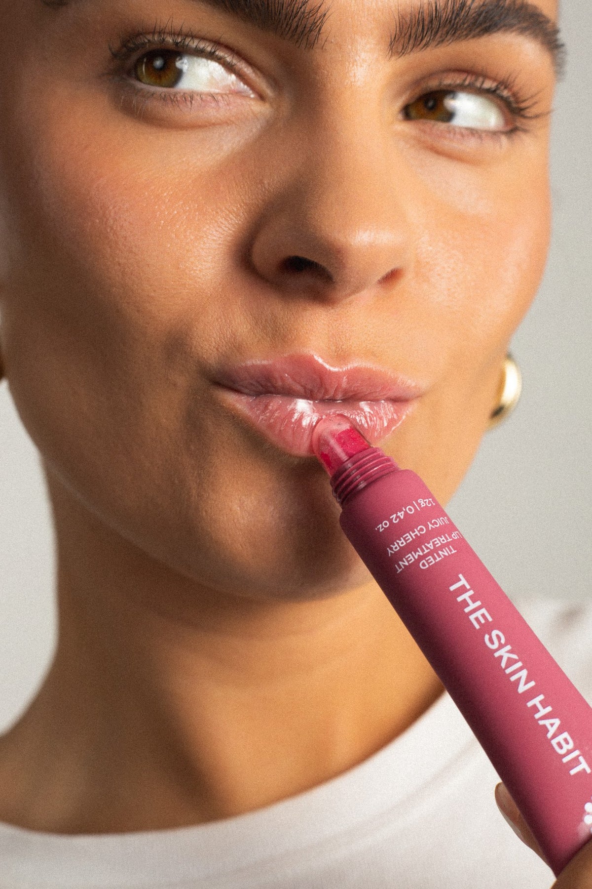 Modell påfører Tinted Lip Treatment Juicy Cherry